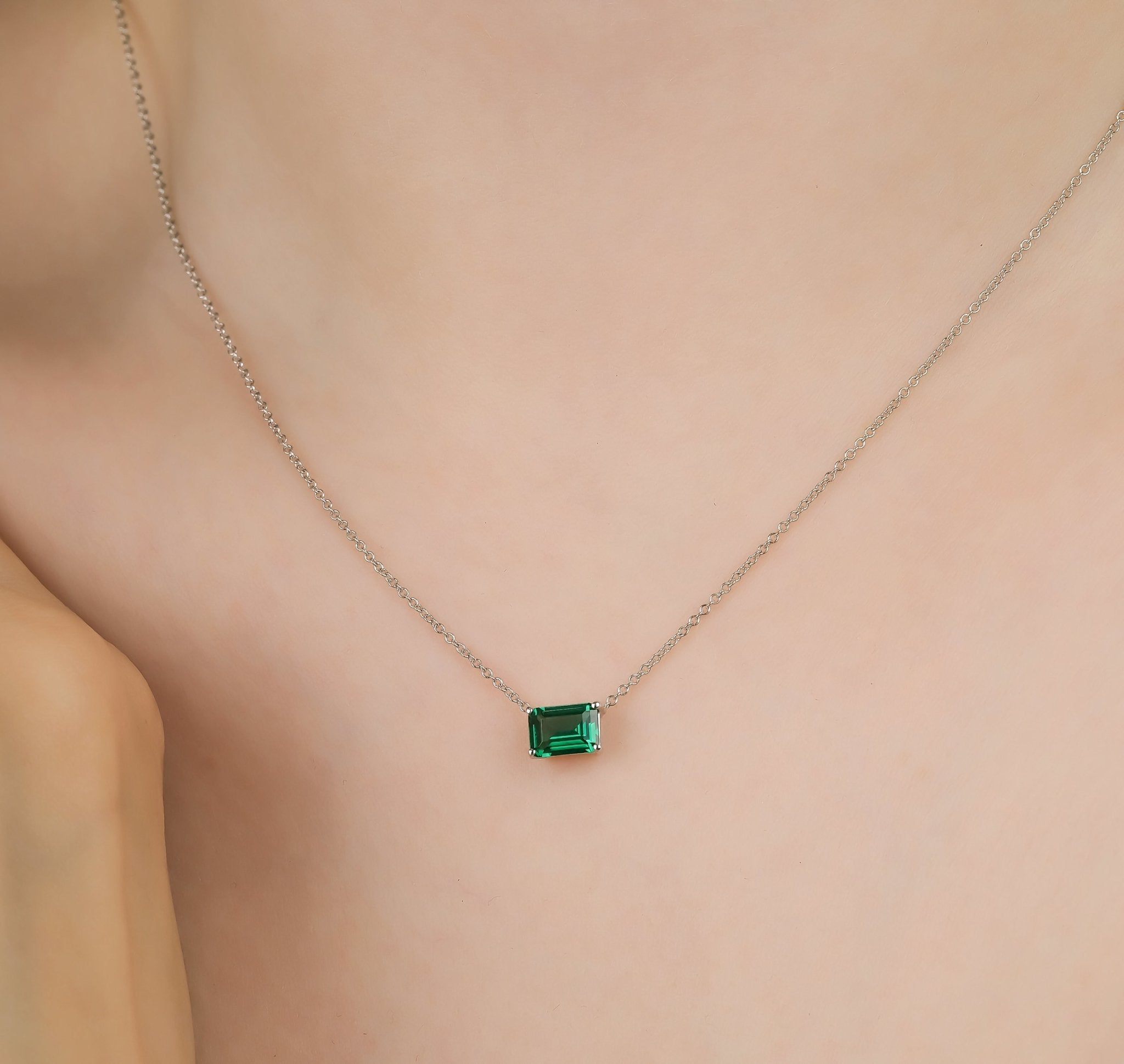 14K white gold emerald cut solitaire emerald necklace on model, showcasing 7x5mm lab-created emerald in a minimalist design.
