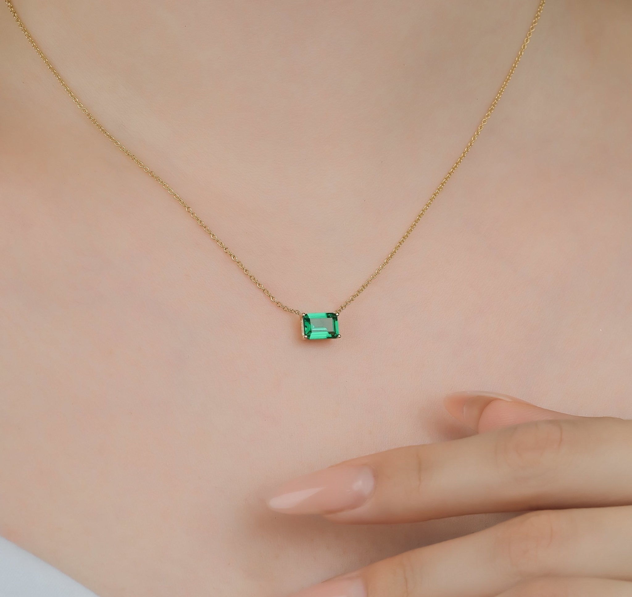 14K white gold emerald cut solitaire emerald necklace on a person, featuring a delicate and minimalist design.