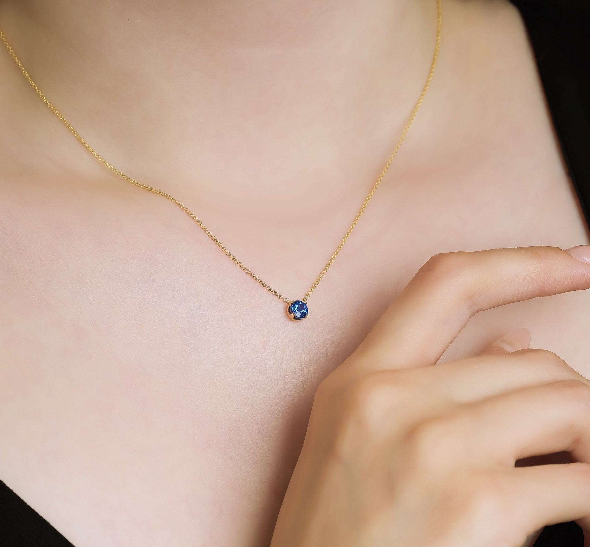 14K white gold prong setting 5mm sapphire solitaire necklace on a model's neck, showcasing its minimalist elegance.