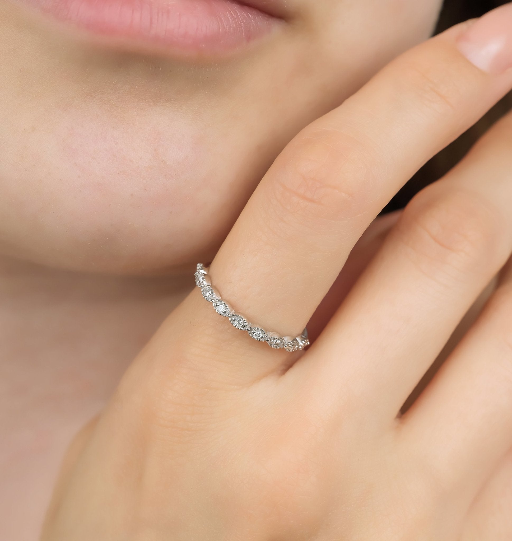Close-up of a woman's hand wearing a minimalist 14K white gold diamond wedding ring with 9 round diamonds.