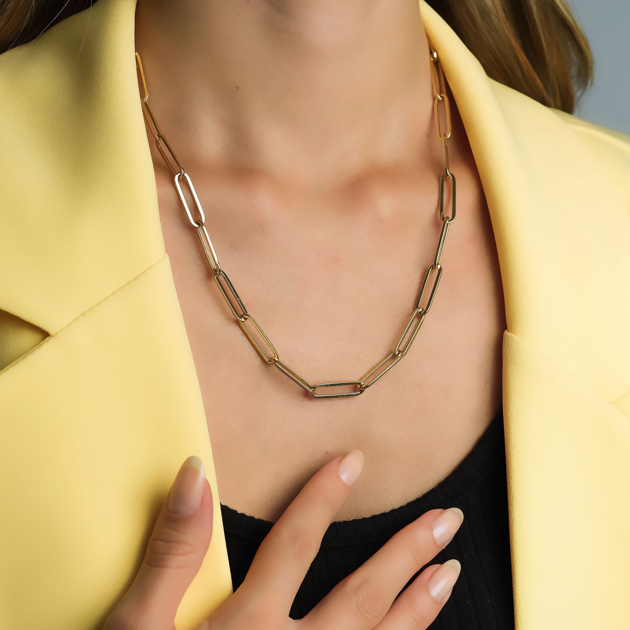 Model wearing a 14K yellow gold 6mm paperclip necklace, styled with a yellow blazer.