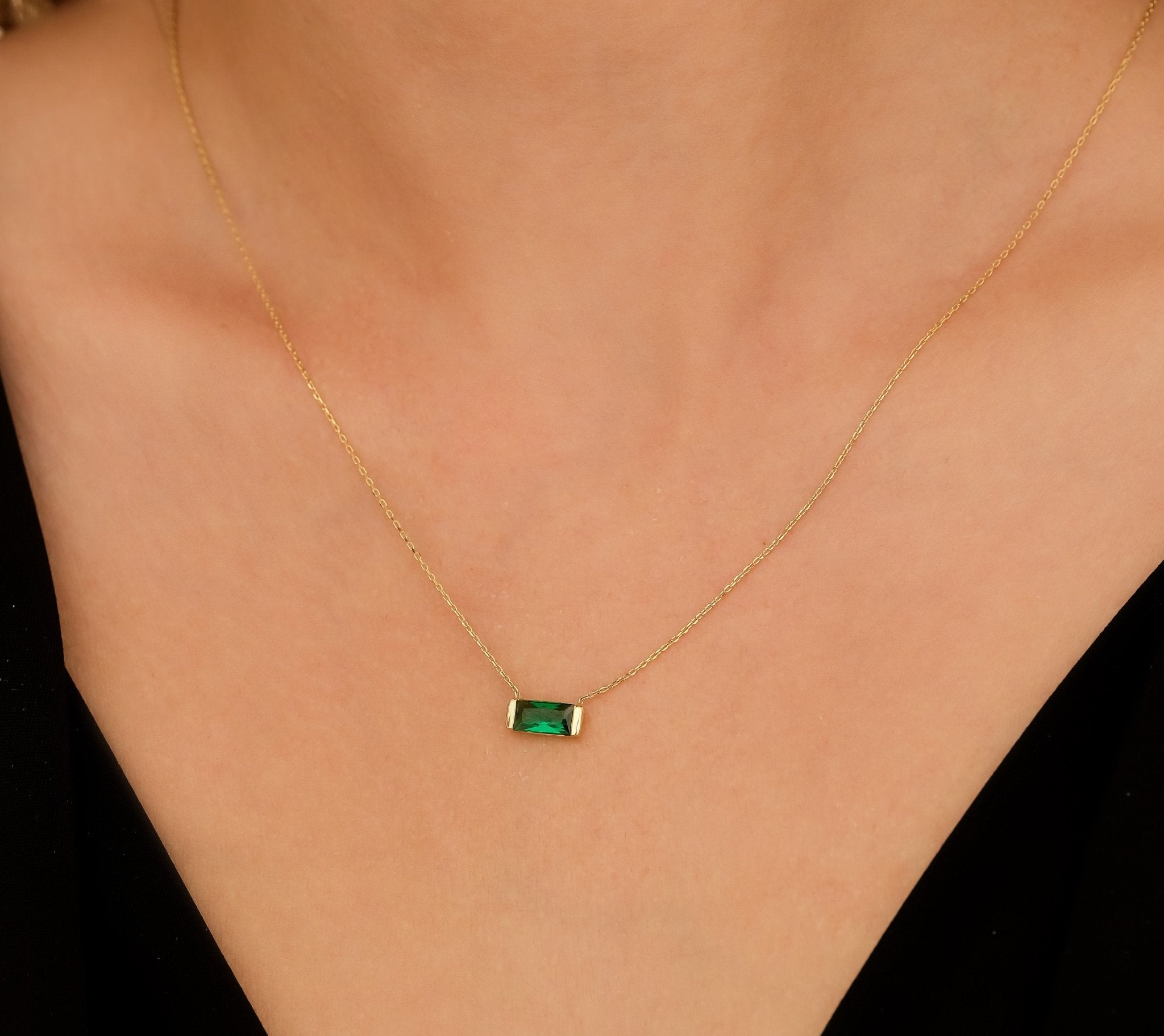 14K yellow gold baguette emerald necklace worn on a model, showcasing its elegance and minimalist design.