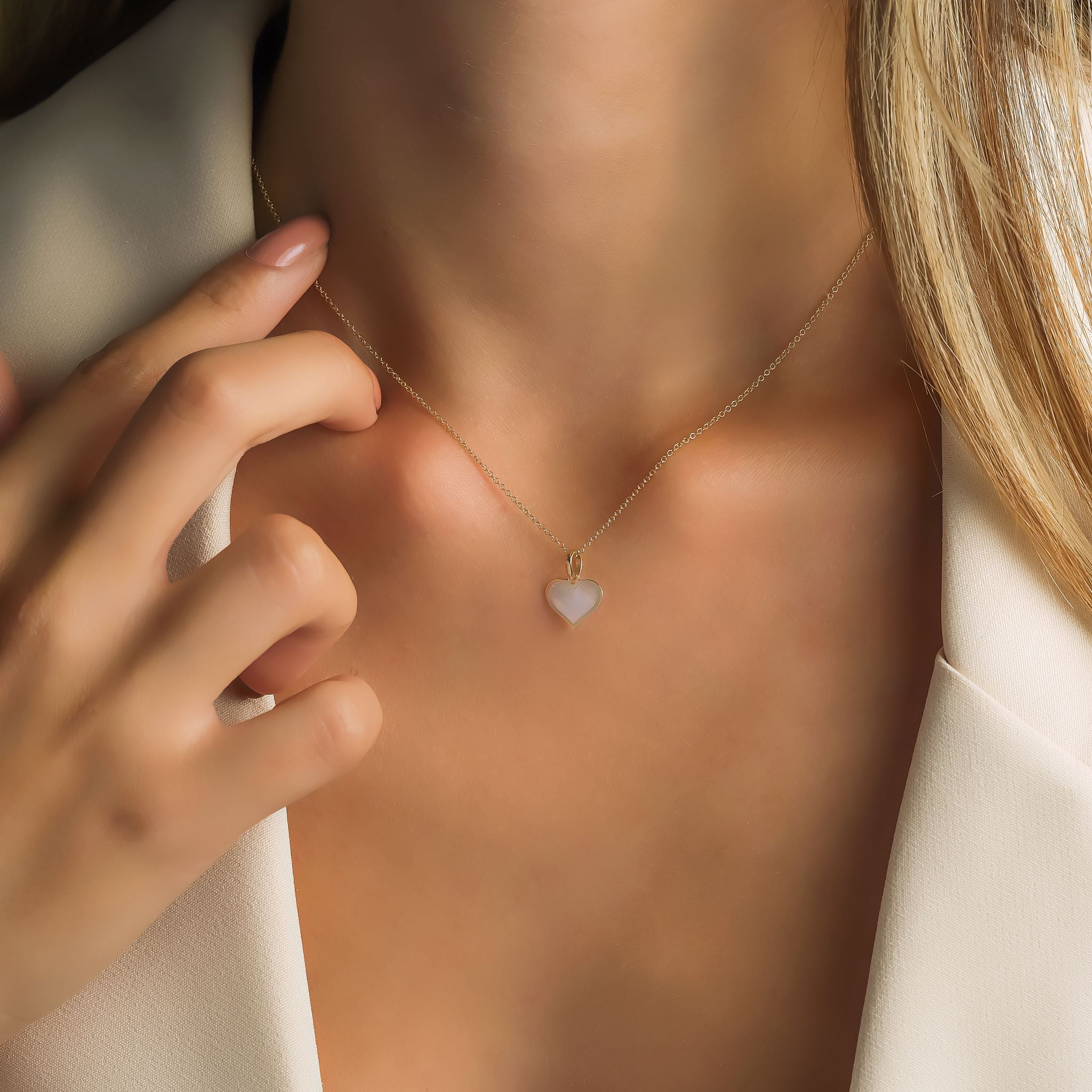 14K yellow gold minimalist necklace with mother of pearl heart pendant worn by woman, showcasing delicate style.