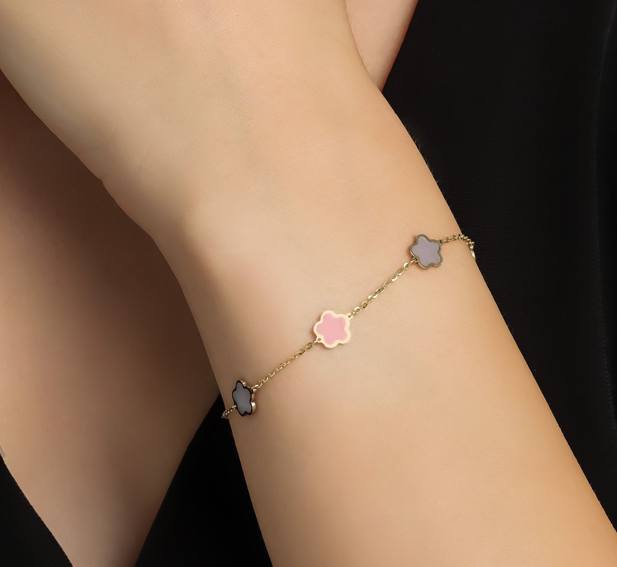 14K yellow gold daisy station bracelet with pink and mother of pearl flowers on a wrist, elegant for everyday wear.