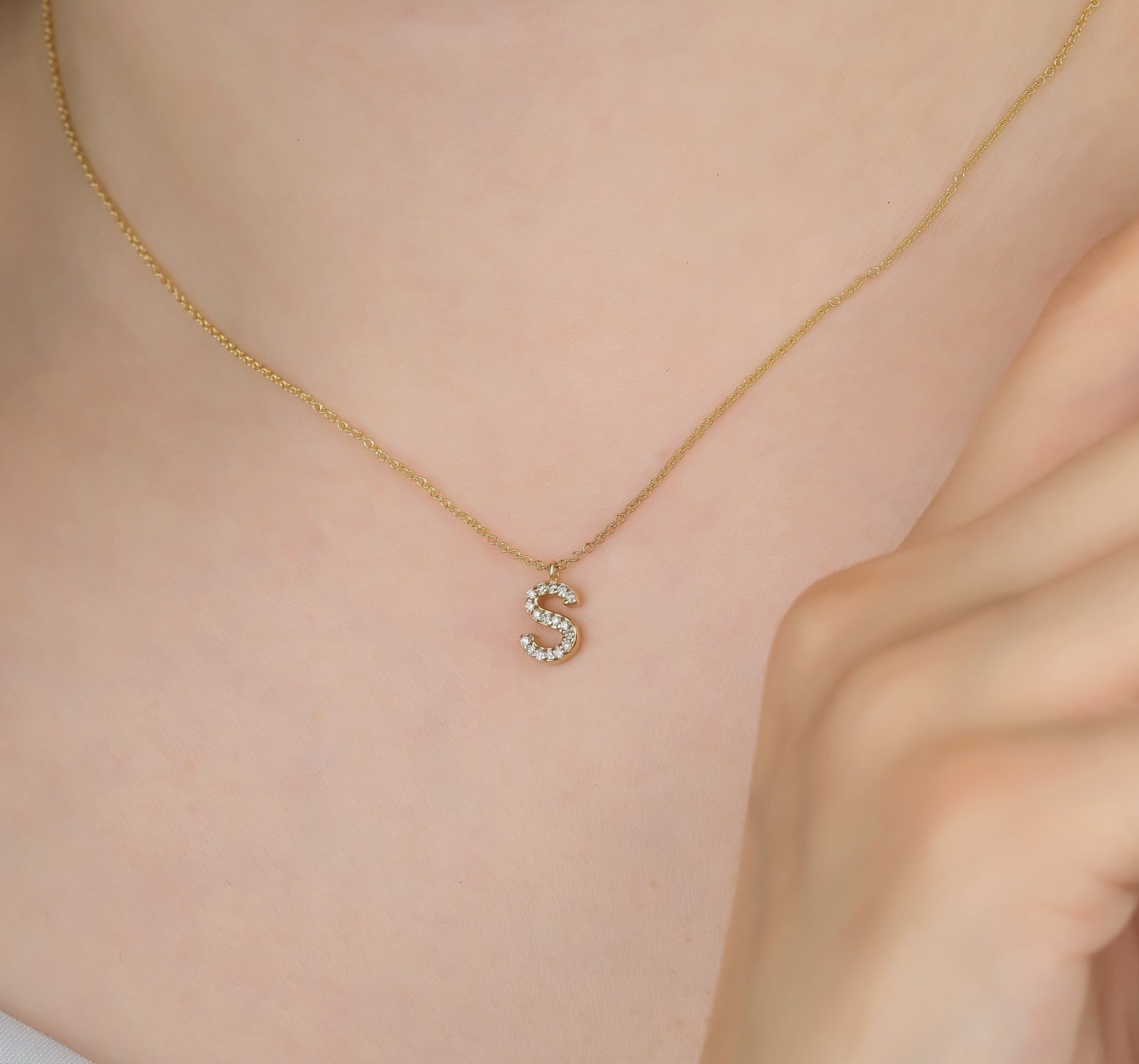 14K yellow gold diamond initial necklace featuring letter 'S', elegantly worn on a delicate chain.