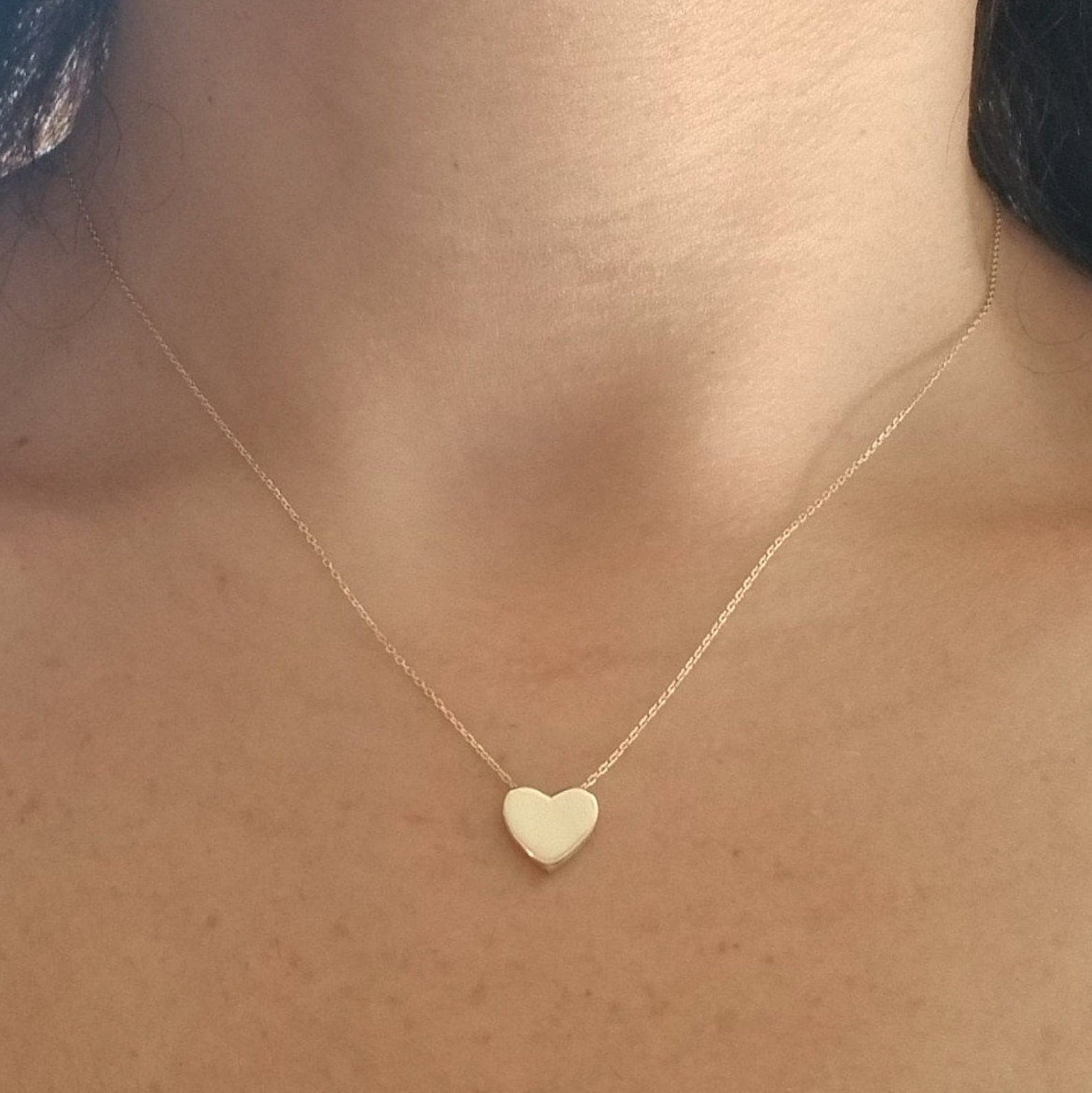 14K yellow gold minimalist heart necklace displayed on a person's neck, perfect for everyday elegance.