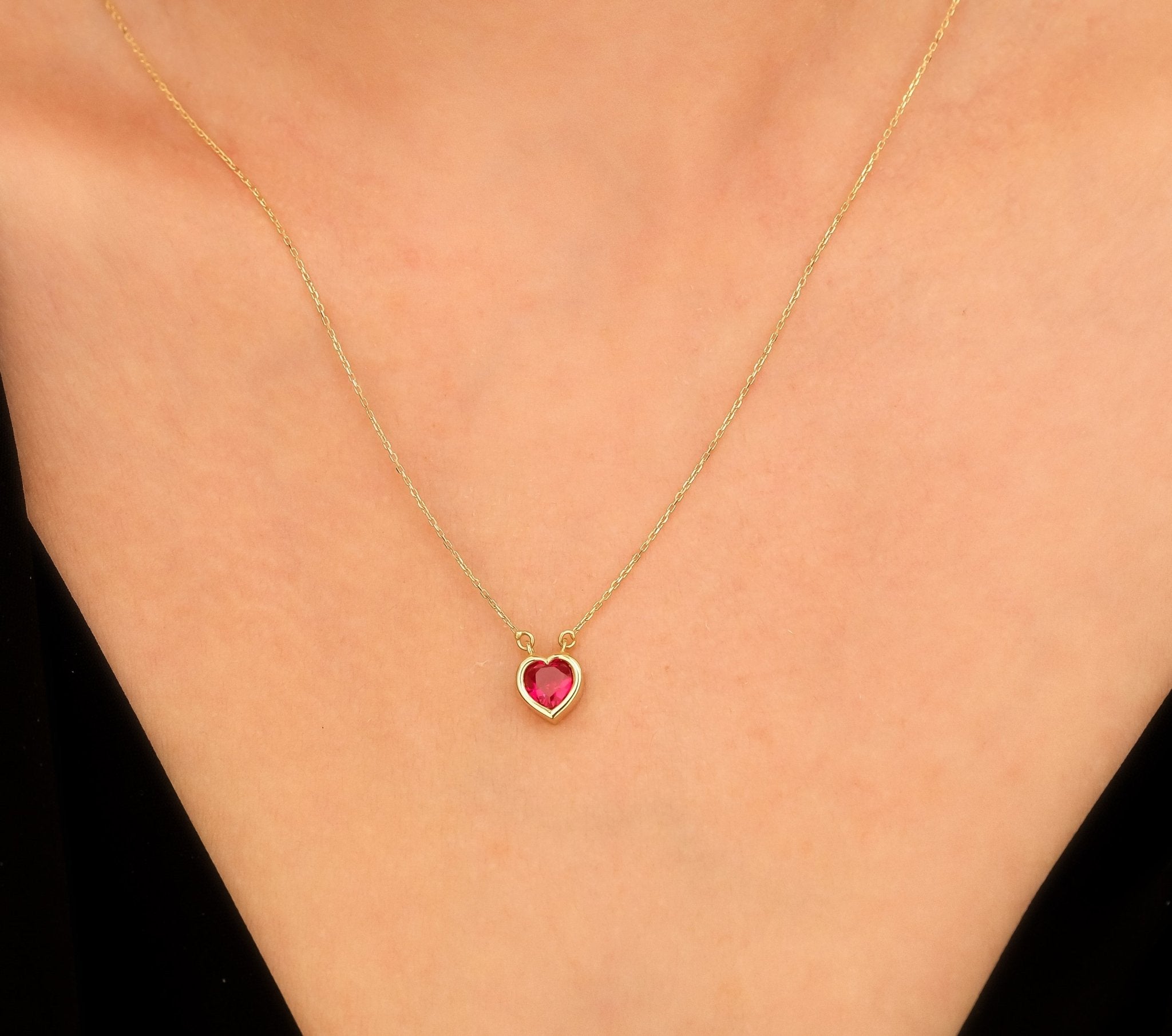 14K yellow gold heart shape ruby necklace worn on a model, showcasing simplicity and elegance.