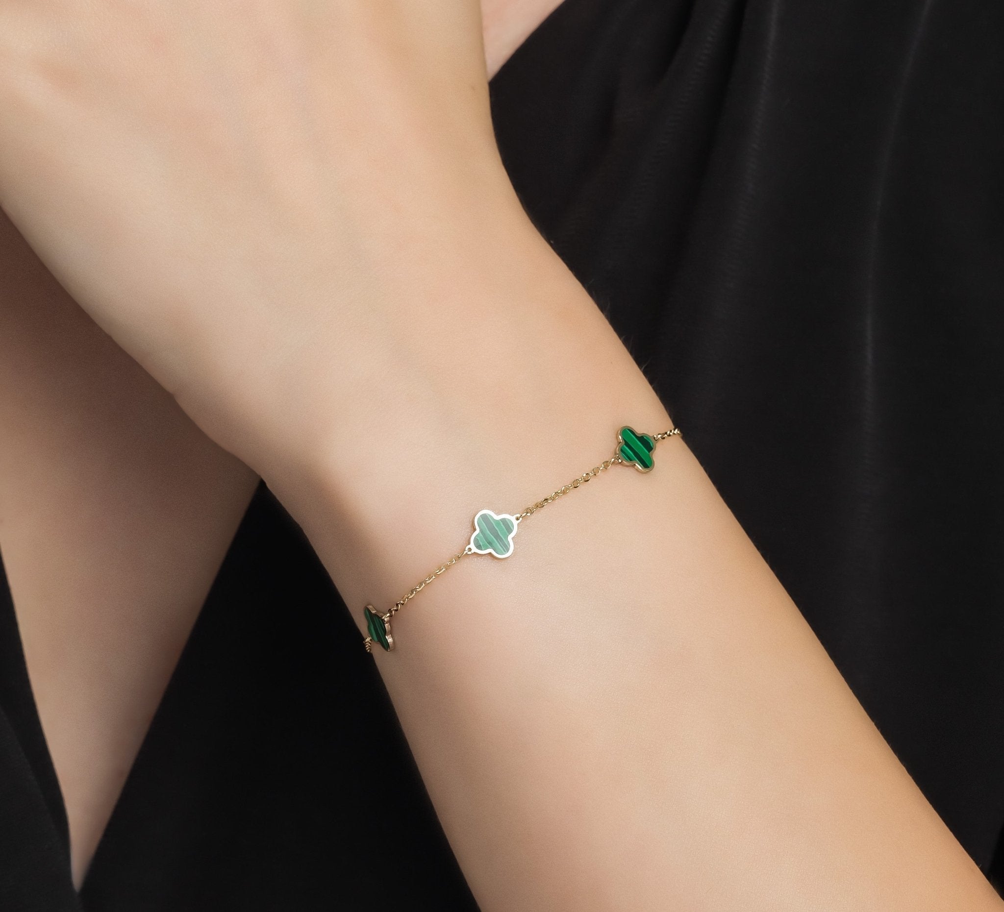 14K solid yellow gold malachite four leaf clover bracelet worn on a wrist, showcasing its elegant design and vibrant colors.