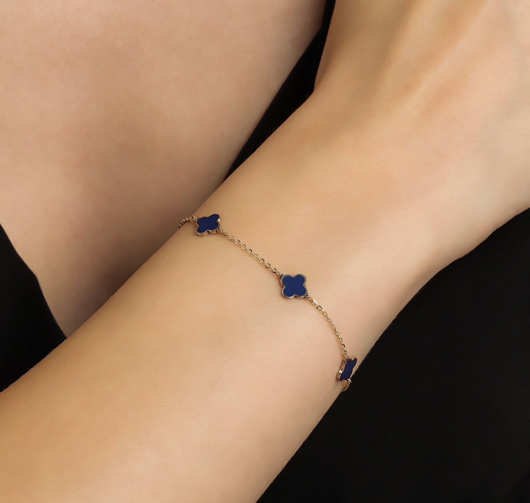 14K yellow gold lapis four leaf clover station bracelet worn on wrist, featuring four blue clover charms, perfect for everyday elegance.