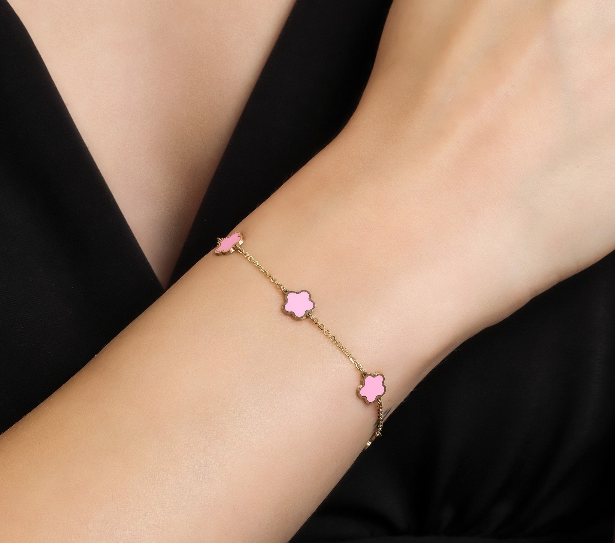 14K yellow gold bracelet with pink daisy blossoms, delicate station design worn on wrist.