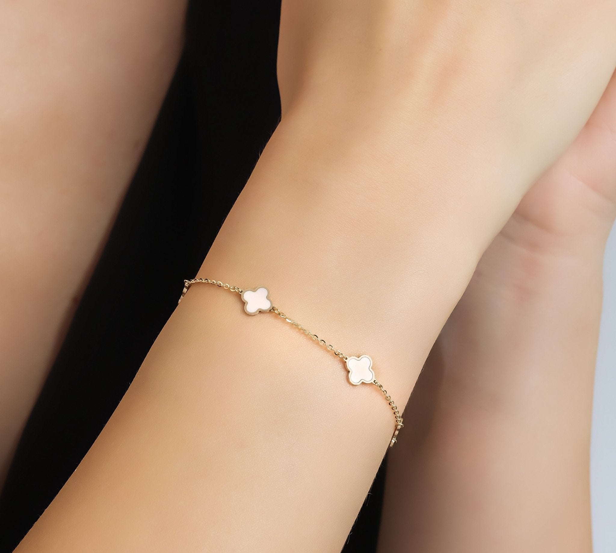 14K solid yellow gold pink four leaf clover bracelet on wrist, showcasing its elegant design and clasp.