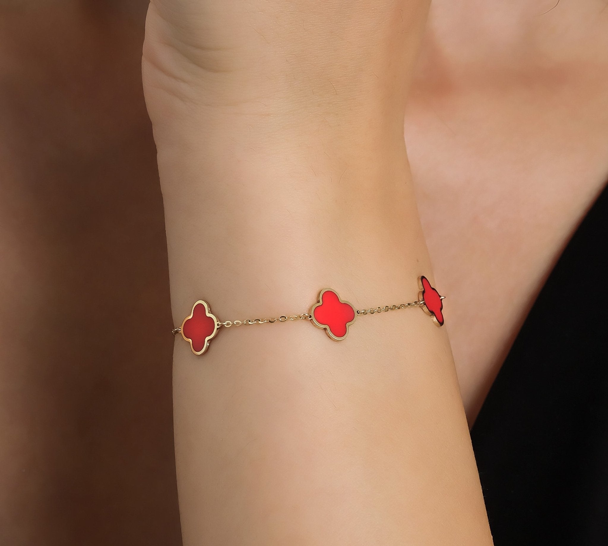 14K solid yellow gold bracelet with red coral four leaf clover design, worn elegantly on a woman's wrist.