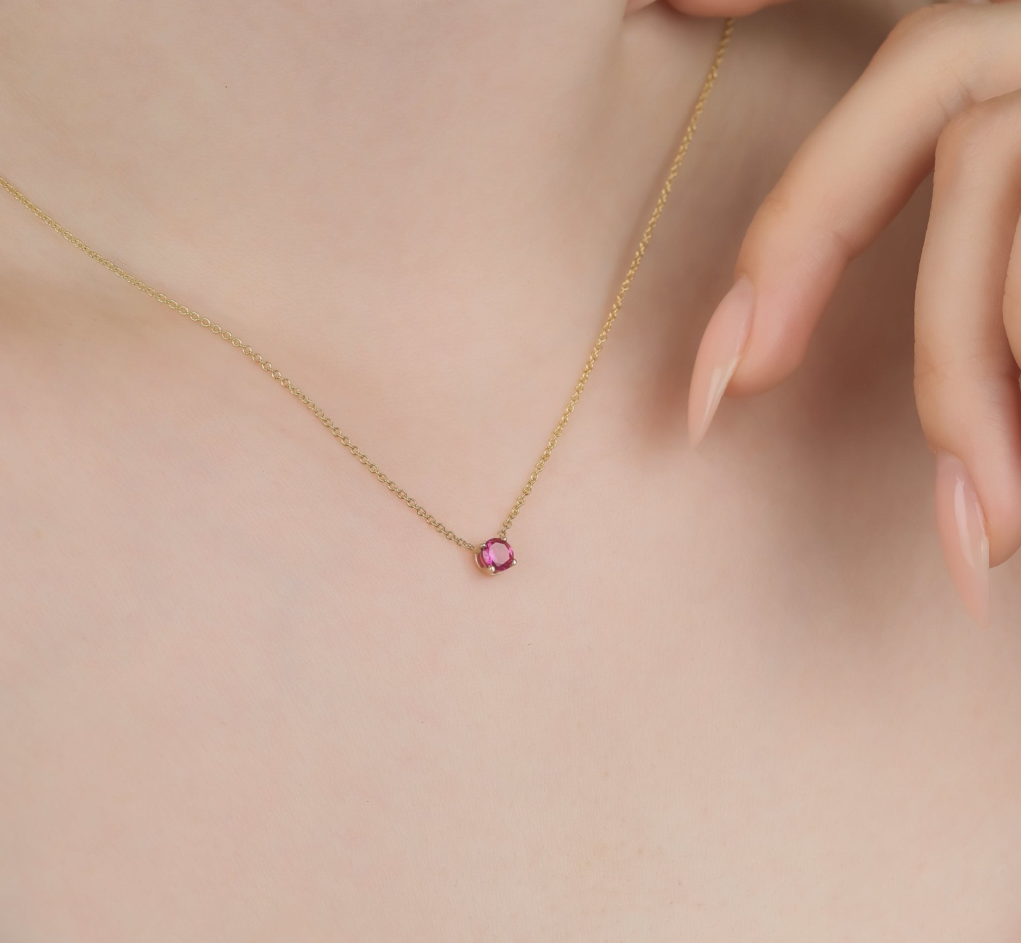 14K yellow gold 5mm prong setting ruby solitaire necklace on a model's neck. Minimalist July birthstone jewelry.