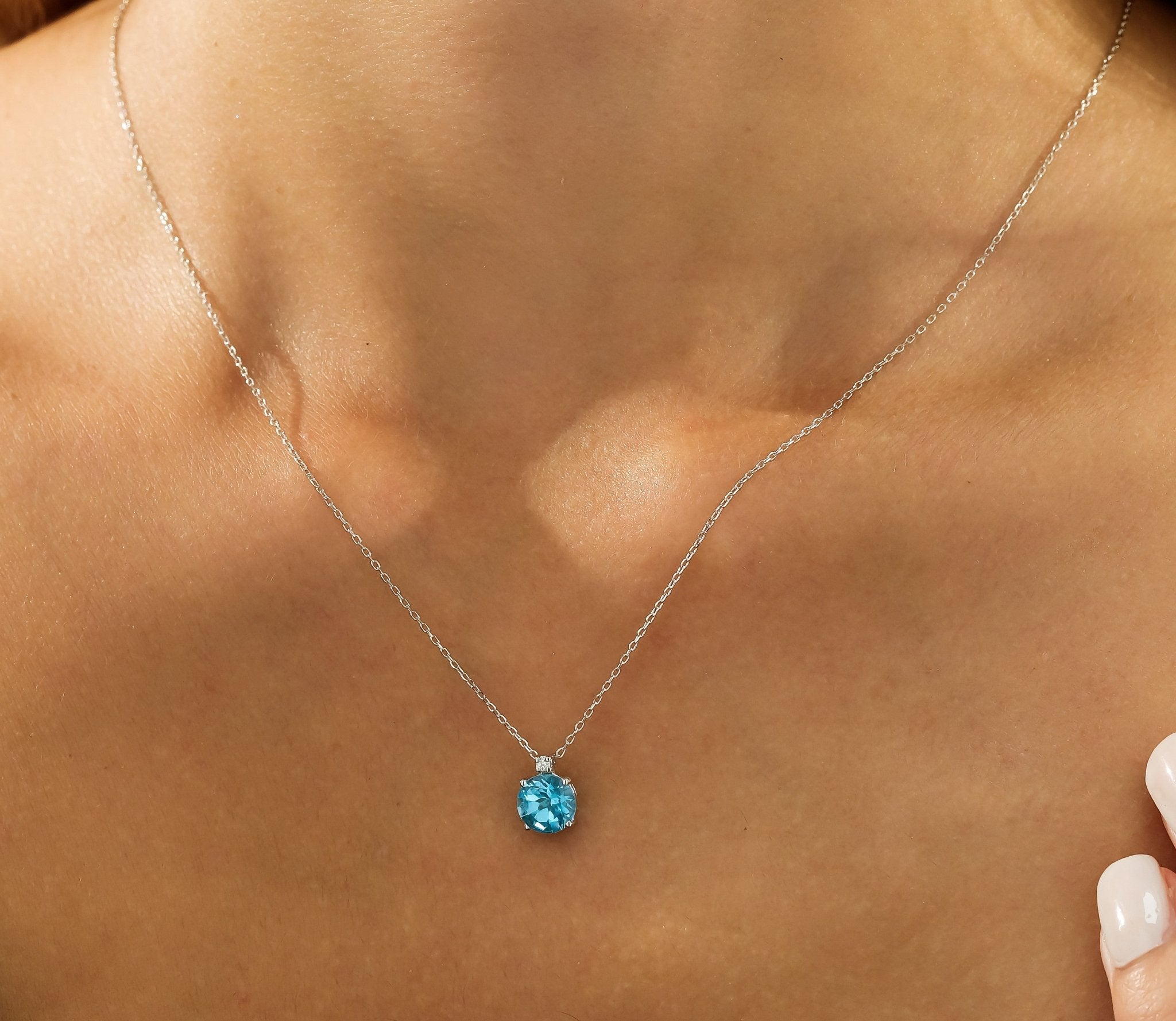 14K white gold necklace featuring a natural blue topaz gemstone pendant, elegantly worn on a model's neck.