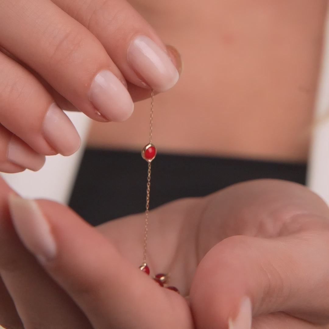 Holding a delicate 14K solid yellow gold beaded station ruby necklace, featuring minimalist design and lab-created rubies.