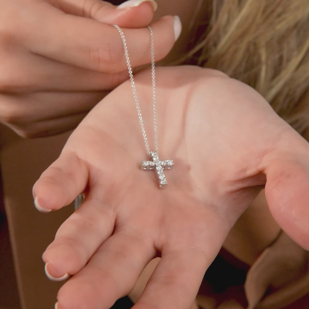 14K white gold cross necklace with 0.55 carat lab-created diamonds held in hand.