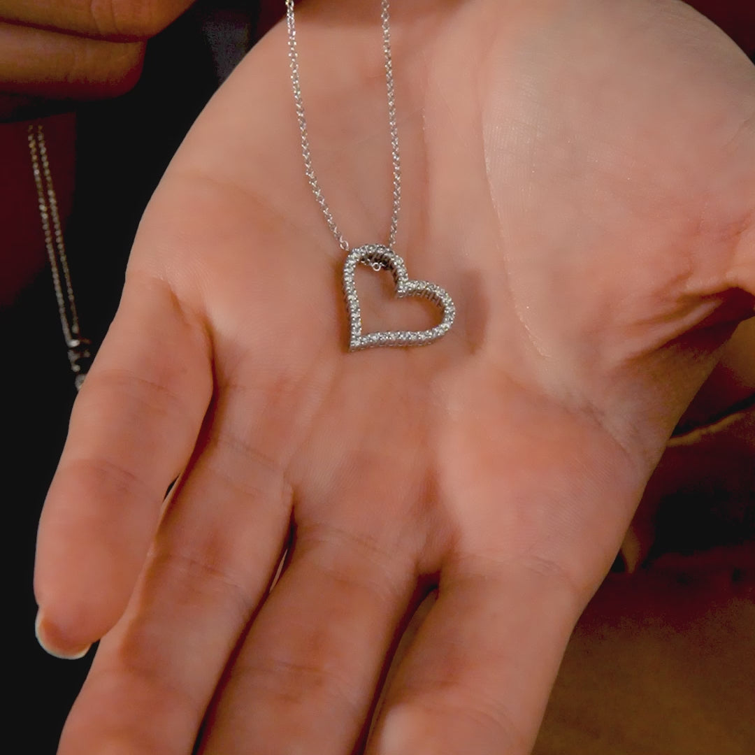 14K white gold heart necklace with natural diamonds, held in a hand, showcasing its sparkle and design.