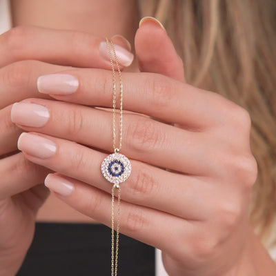 Model showcasing a 14K solid yellow gold evil eye bracelet, featuring a delicate design with CZ accents.