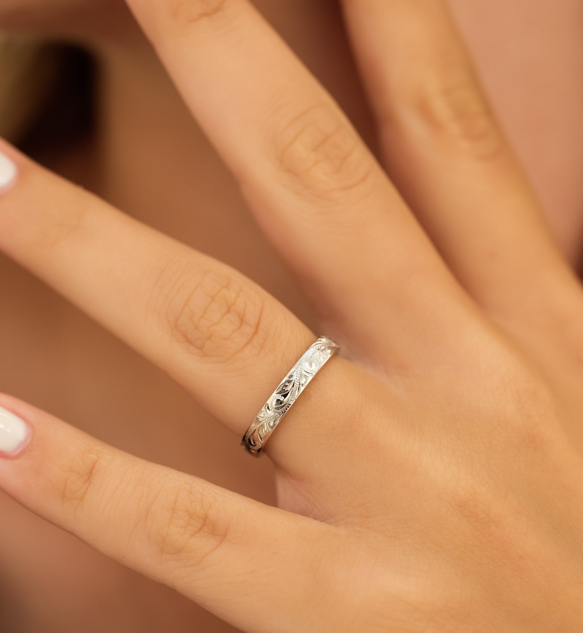 Elegant 3mm hand engraved white gold wedding band showcased on a finger with leaf motifs and shiny finish.