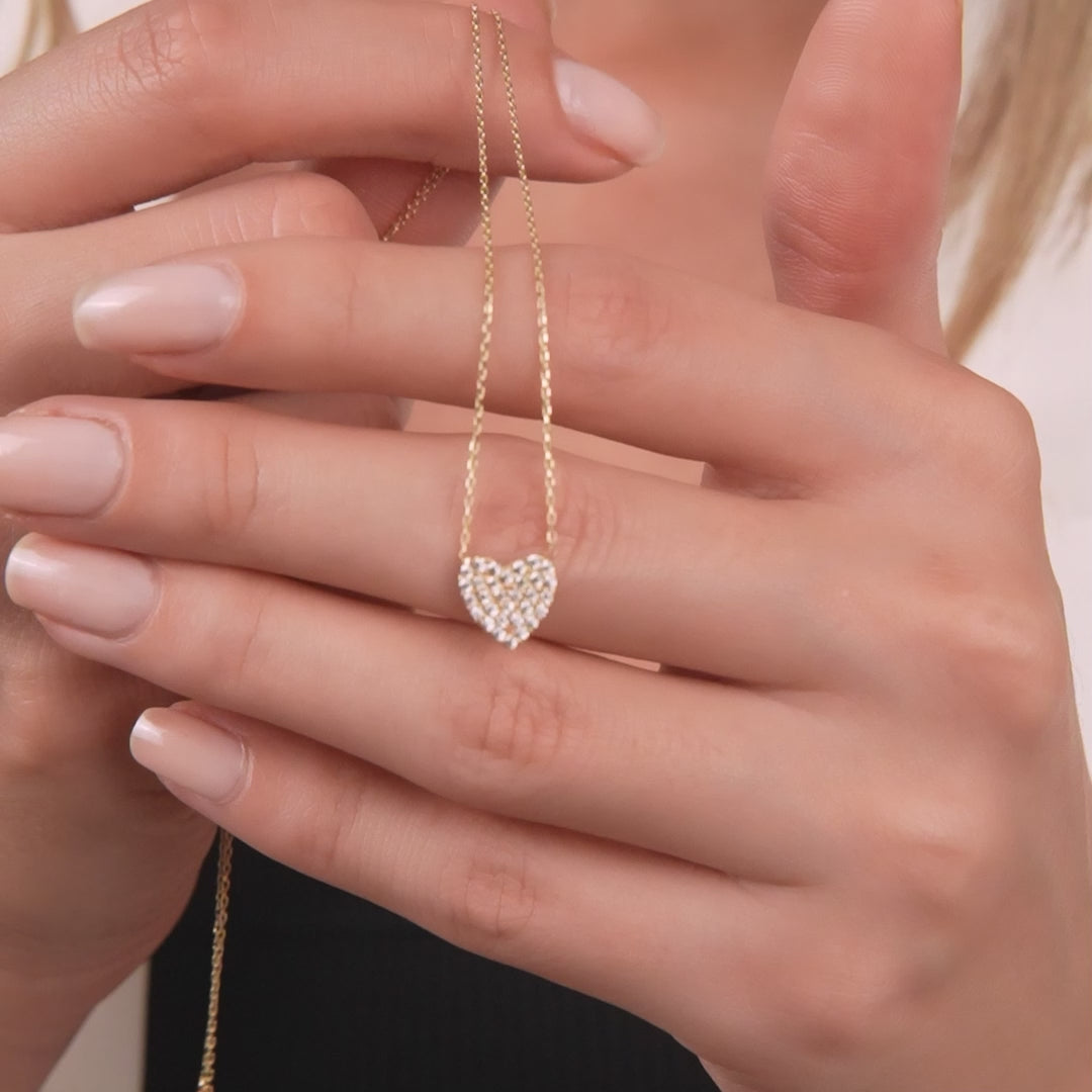 Dainty heart necklace in 14K solid yellow gold with CZ, showcased by a woman holding the pendant.