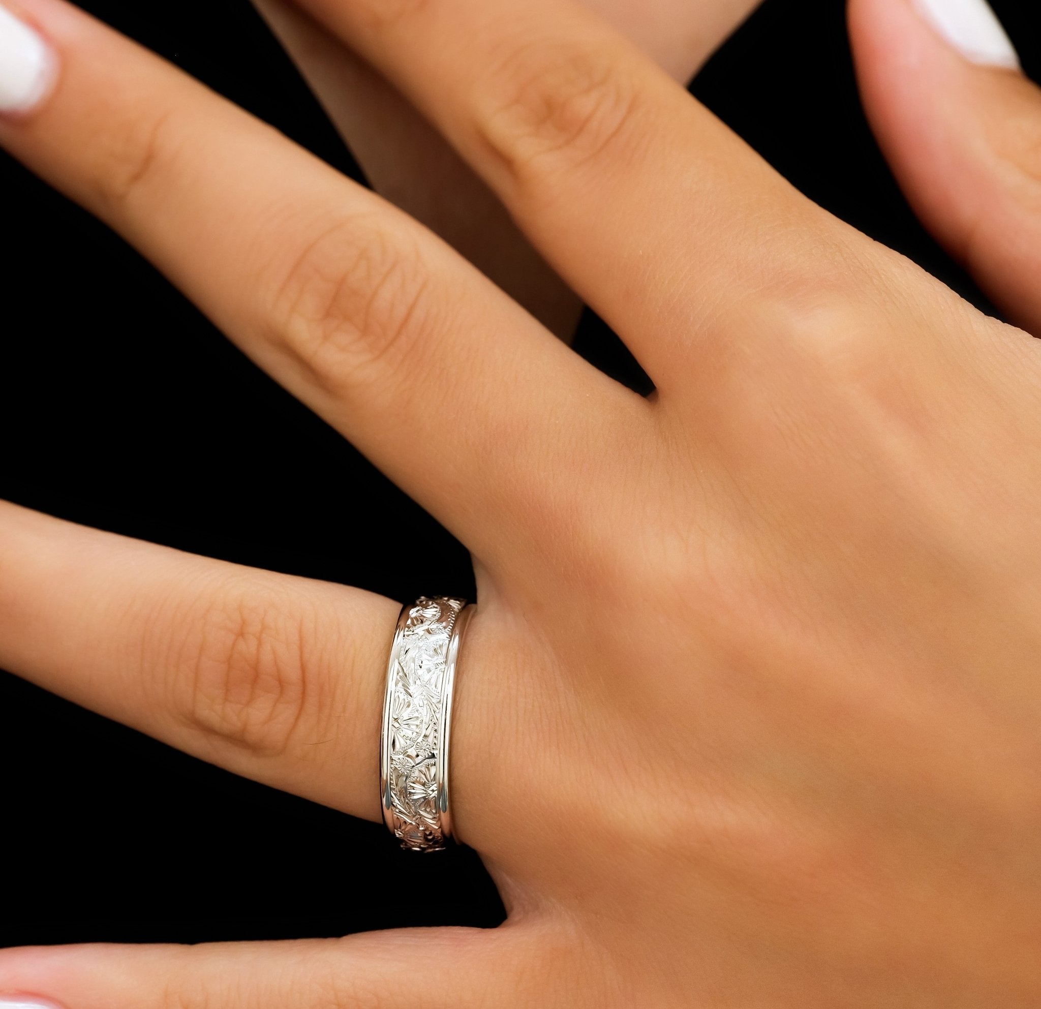Hand wearing a 6mm 10K 14K 18K white gold hand engraved wedding band with shiny leaf motifs.