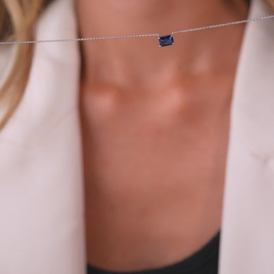14K white gold emerald cut sapphire solitaire necklace worn with a minimalist outfit, highlighting its elegance and simplicity.