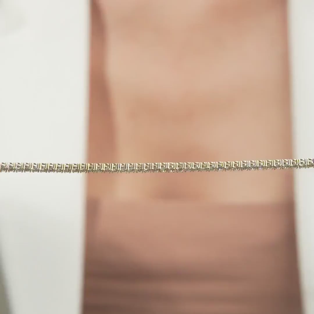 Close-up of a 14K solid yellow gold tennis necklace showcasing diamond detailing, elegantly displayed against a blurred background.
