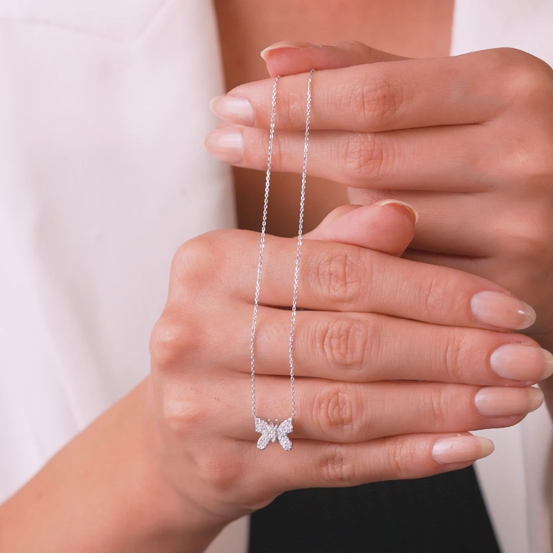 14K solid white gold diamond butterfly necklace worn on model's hand, highlighting intricate design and sparkle.