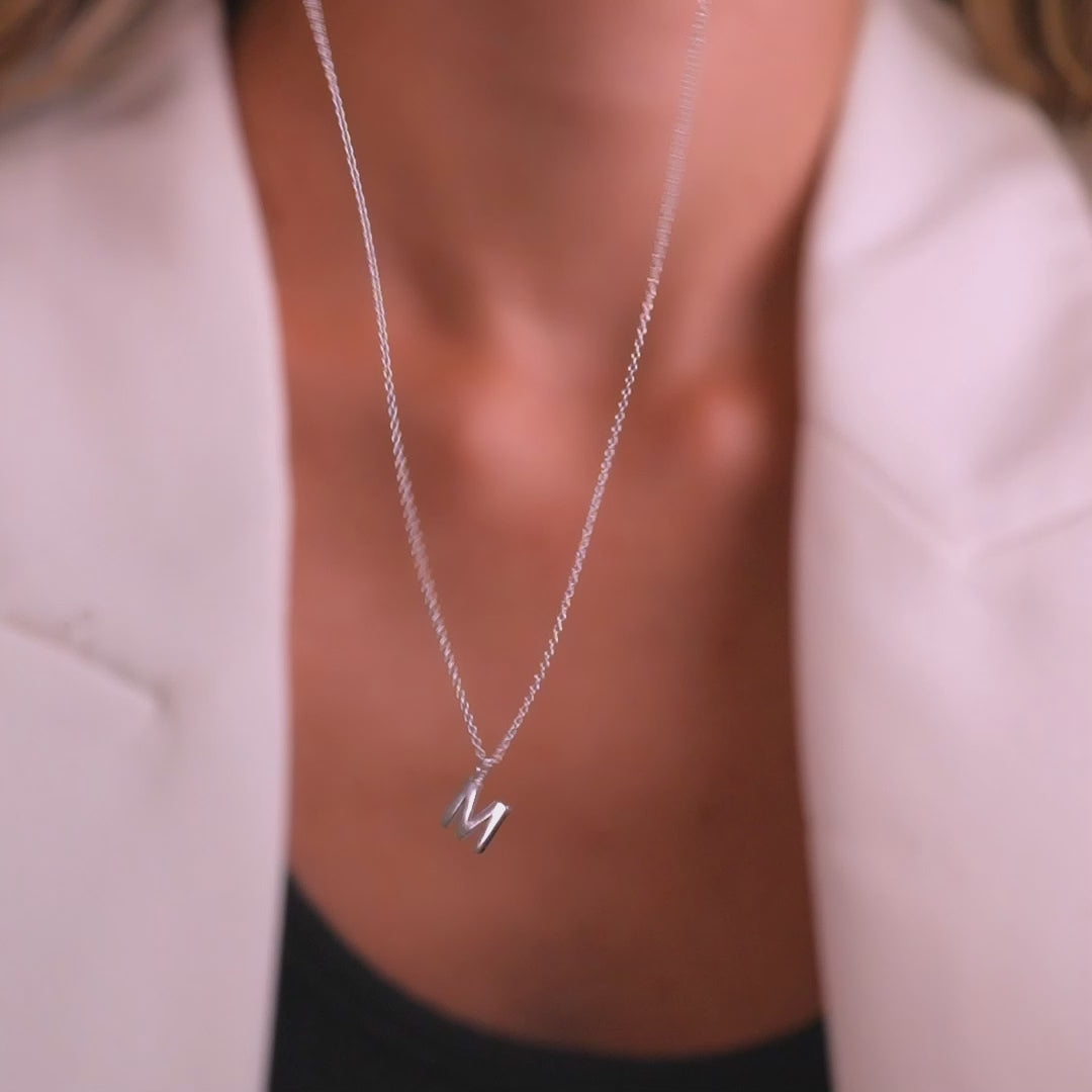 14K solid white gold initial necklace featuring the letter M, worn against a stylish outfit.