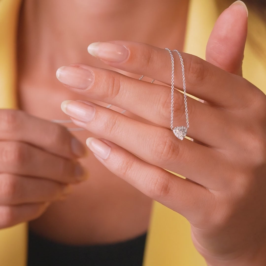 Woman wearing a minimalist diamond heart necklace on a delicate chain, showcasing its elegance and sparkle.
