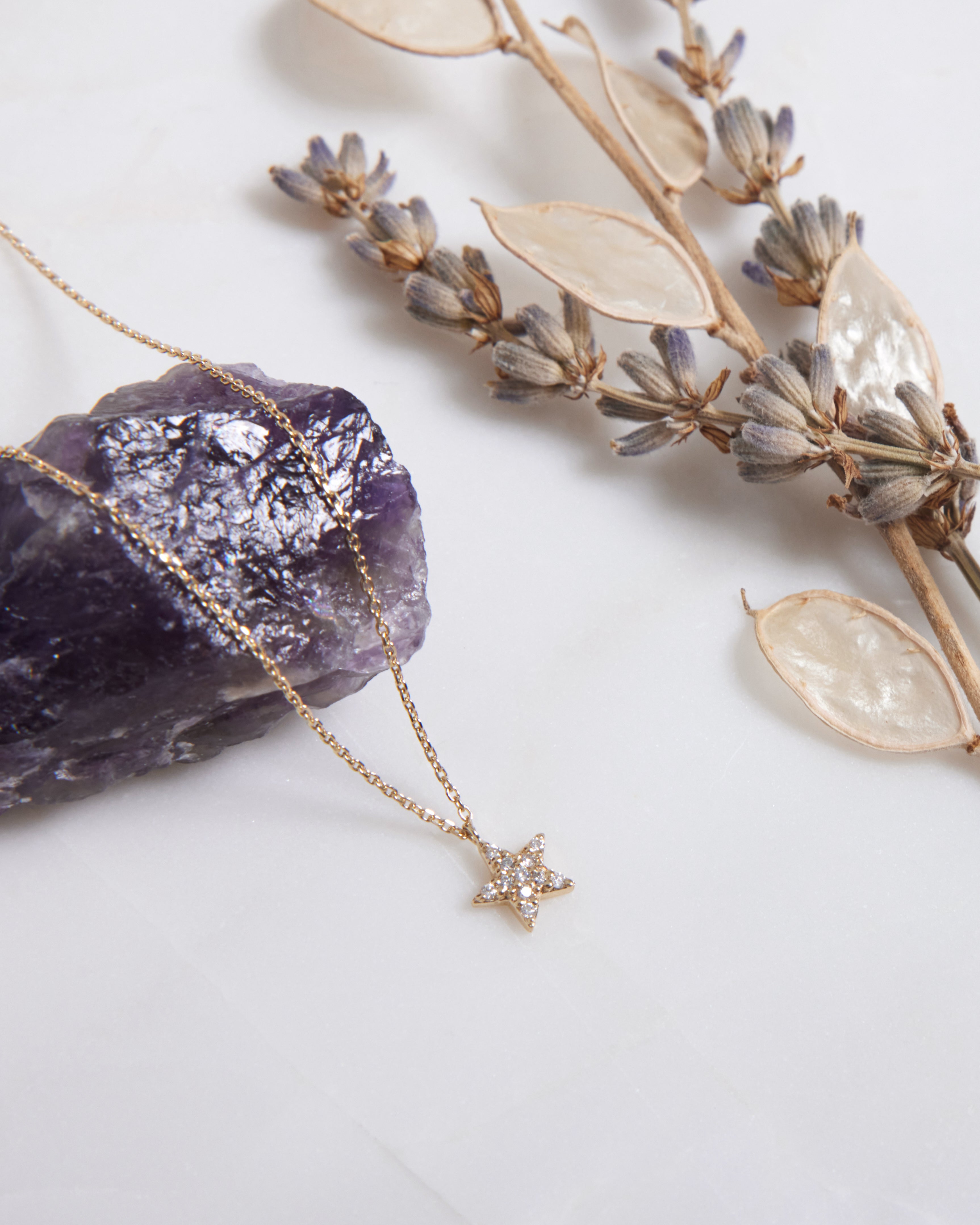 14K solid yellow gold diamond star necklace displayed with amethyst and dried flowers, showcasing its minimalist design.