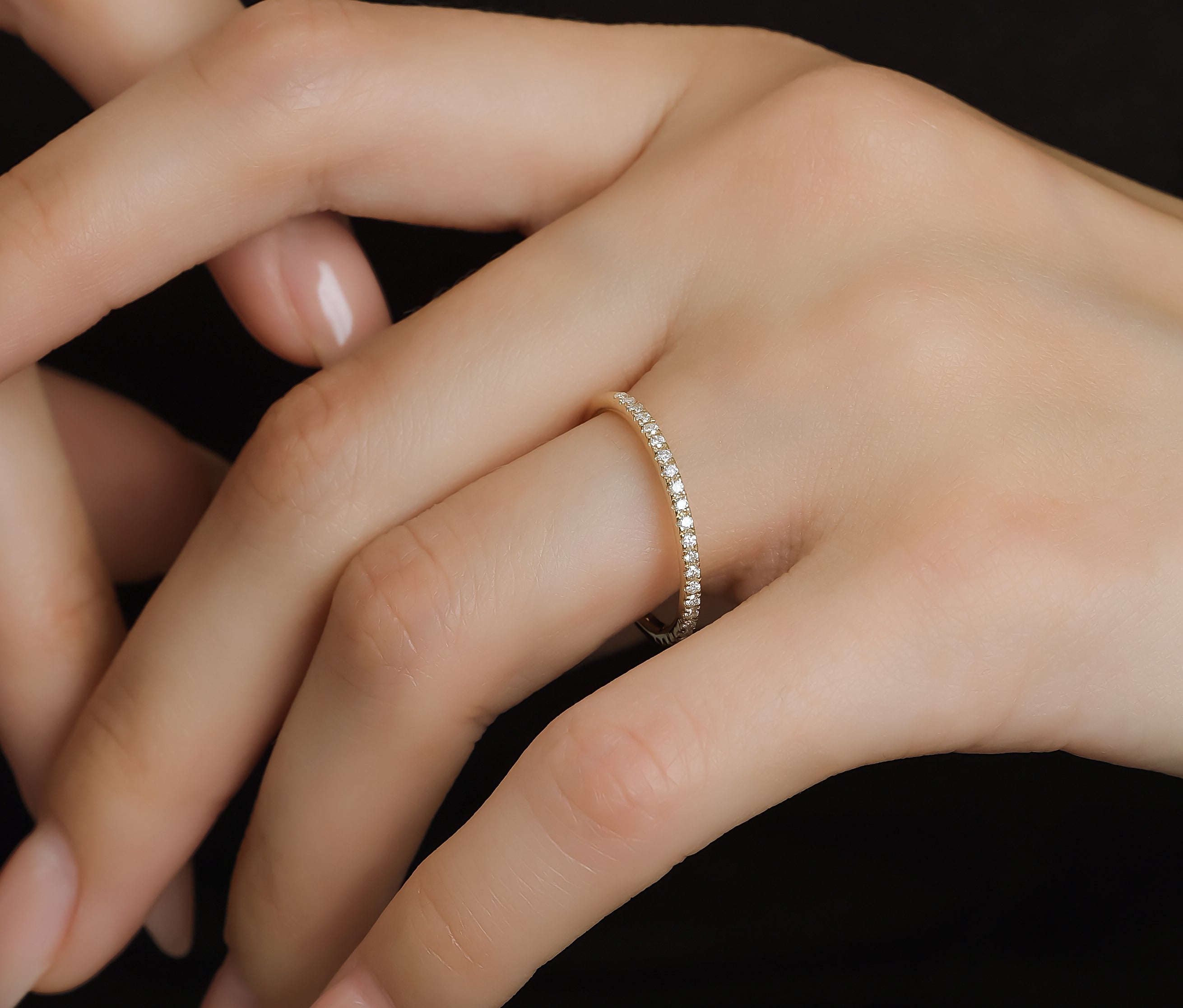 Model wearing a 14K gold half eternity diamond wedding ring with a micro pave setting on her hand.