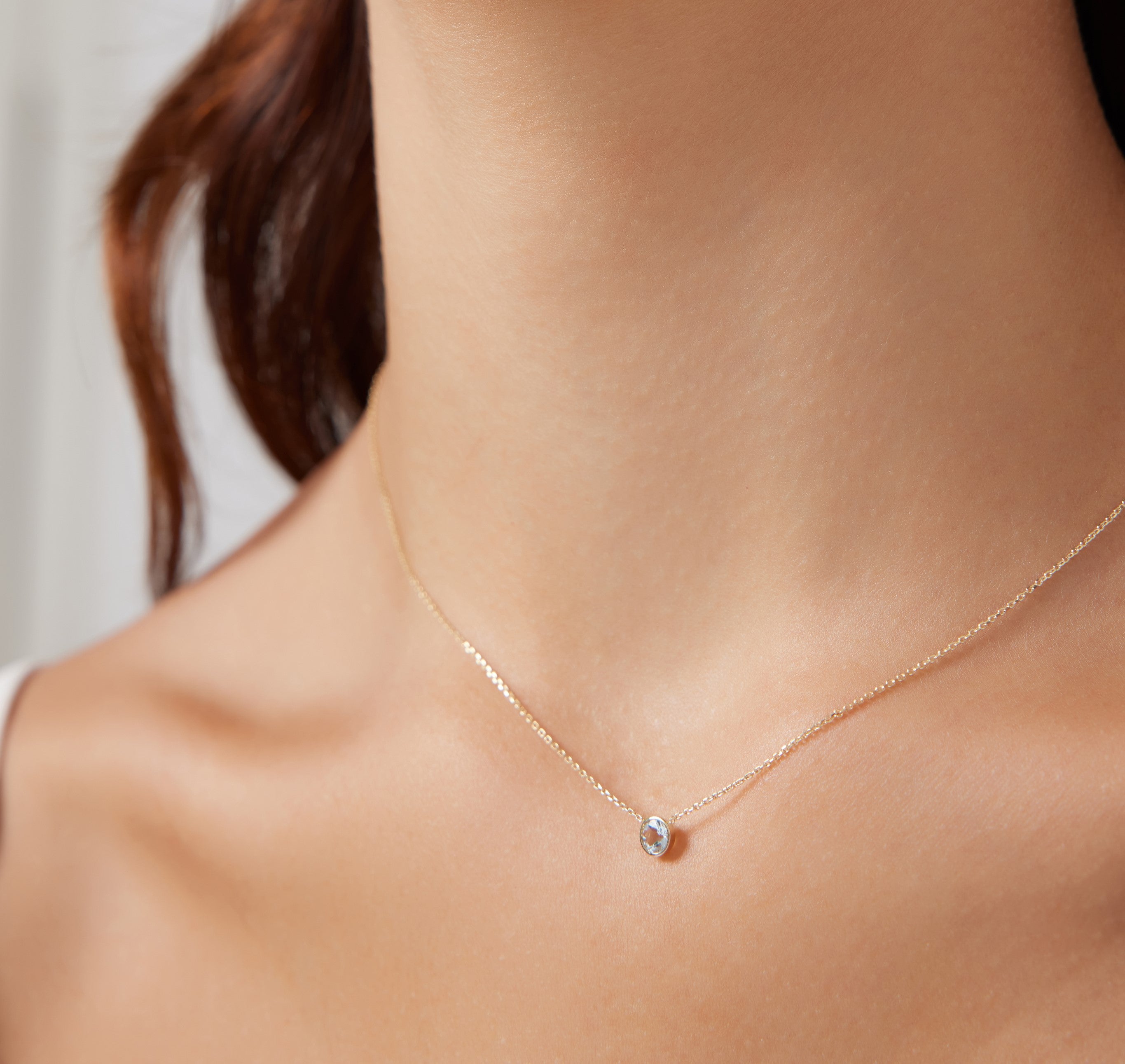 Dainty 14K yellow gold necklace featuring a 4mm bezel set solitaire aquamarine pendant, perfect for everyday wear.