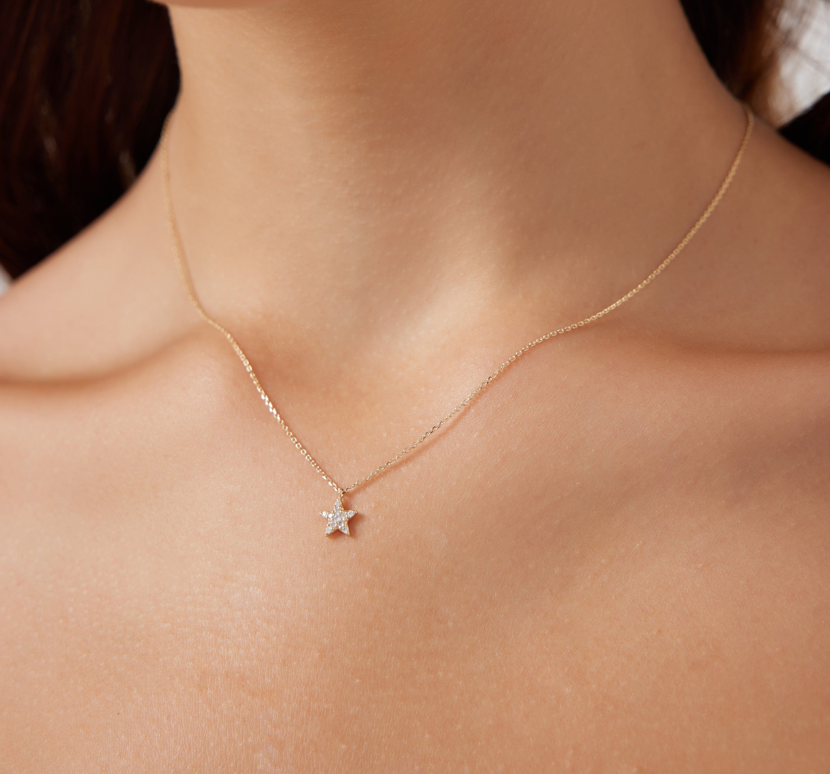 14K solid yellow gold diamond star necklace worn around the neck, featuring a delicate star pendant.