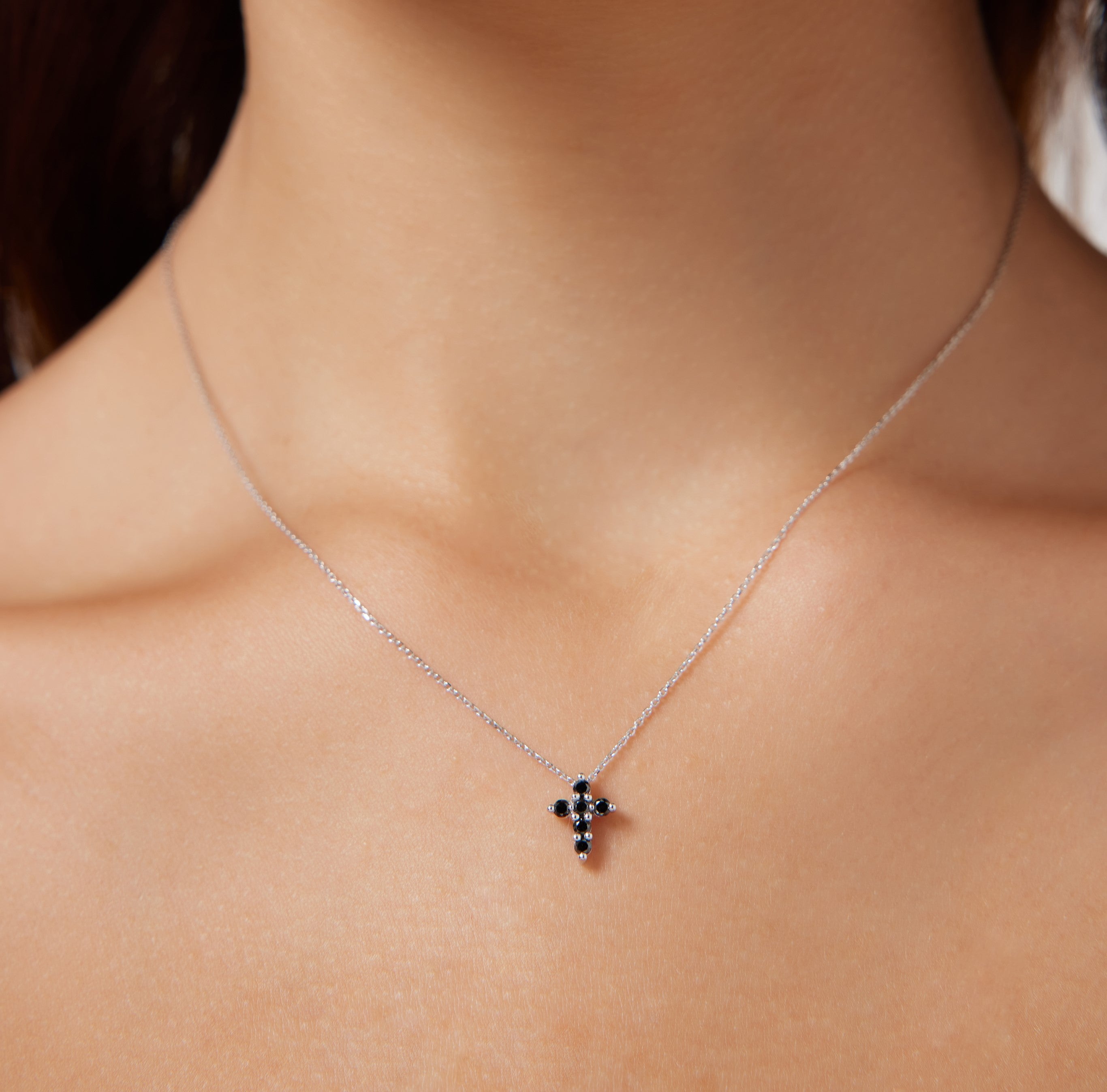14K solid white gold minimalist cross necklace featuring black diamonds, worn elegantly on a model.