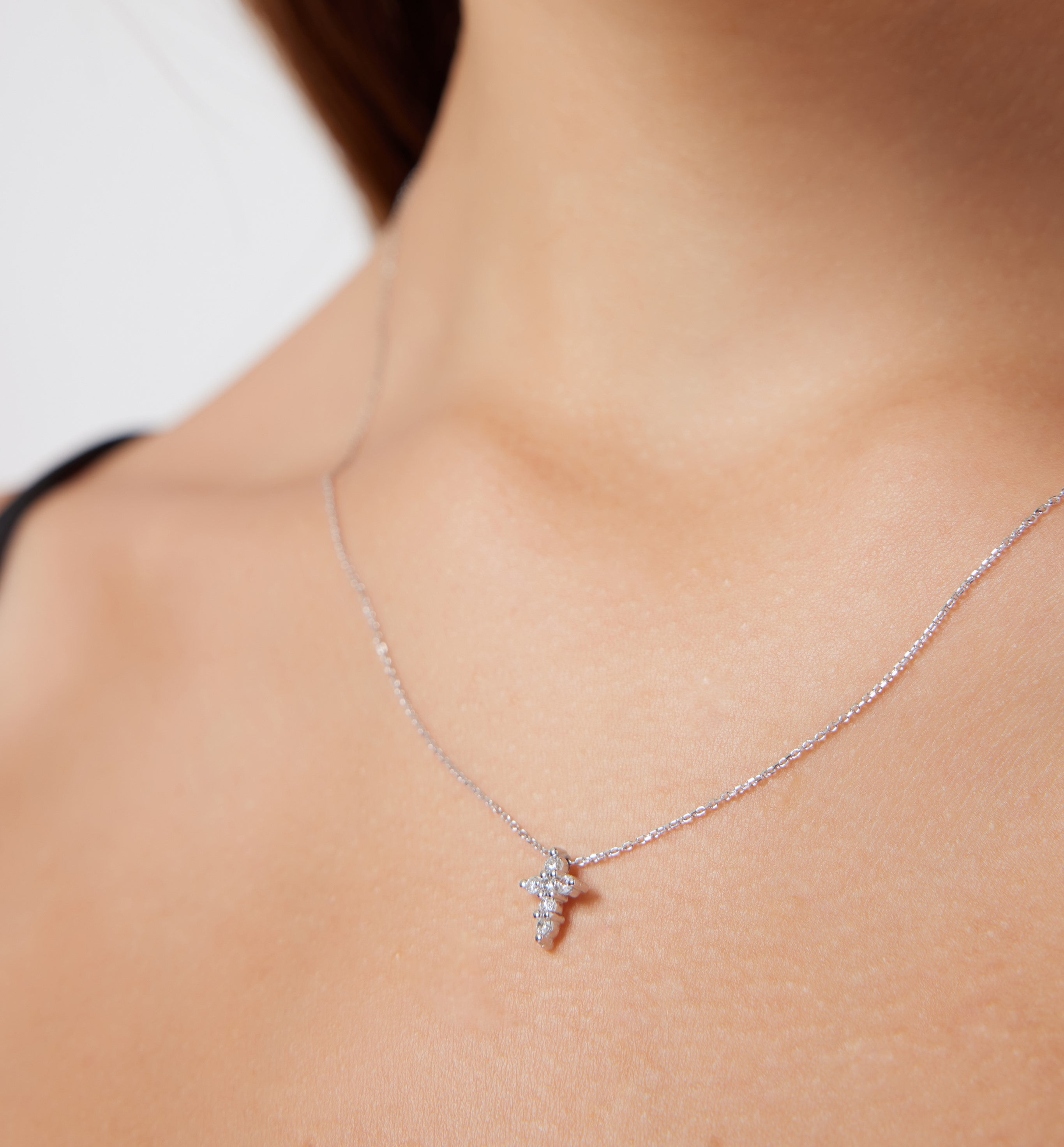 14K solid white gold minimalist diamond cross necklace worn, showcasing its dainty design and sparkling diamonds.