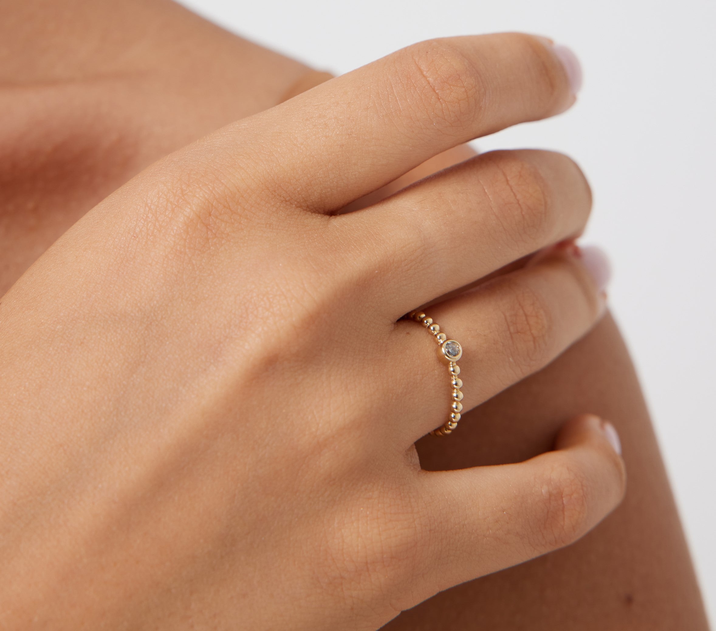 14K yellow gold minimalist diamond solitaire wedding ring worn on a woman's hand, showcasing elegant design and sparkle.