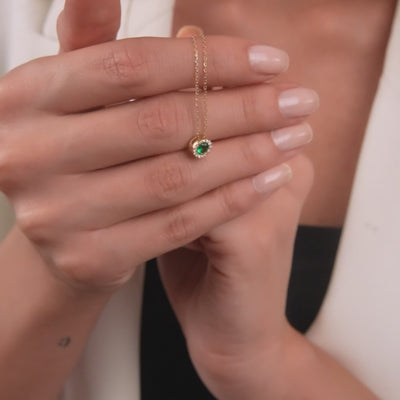 Model holding a dainty 14K solid yellow gold solitaire emerald necklace, showcasing its minimalist design and elegance.