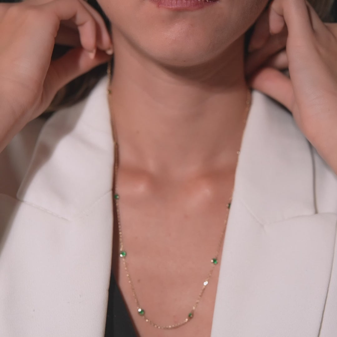 Model wearing a 14K gold emerald station necklace, featuring delicate emerald gemstones and a stylish design.