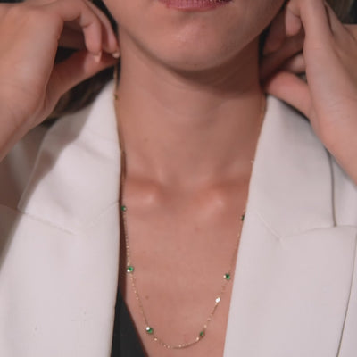 Model wearing a 14K gold emerald station necklace, featuring delicate emerald gemstones and a stylish design.