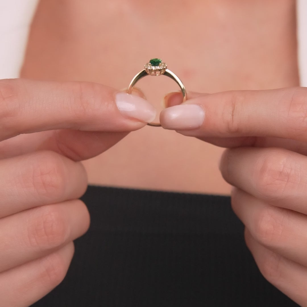 14K yellow gold oval emerald ring held in hands, featuring CZ side stones, perfect for women's wedding band.