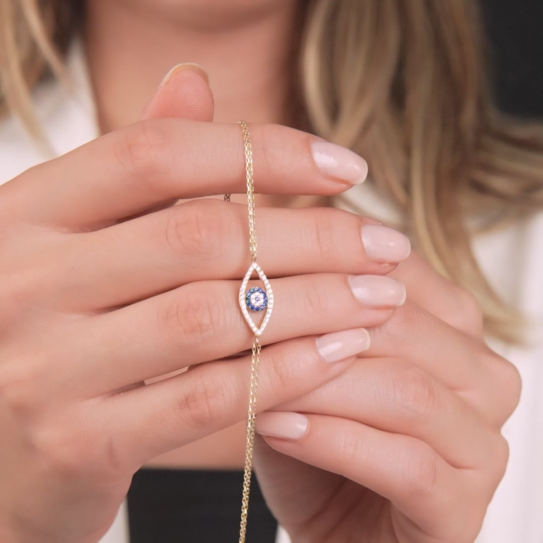 14K solid yellow gold evil eye bracelet held in hand, featuring a delicate design with CZ accents.