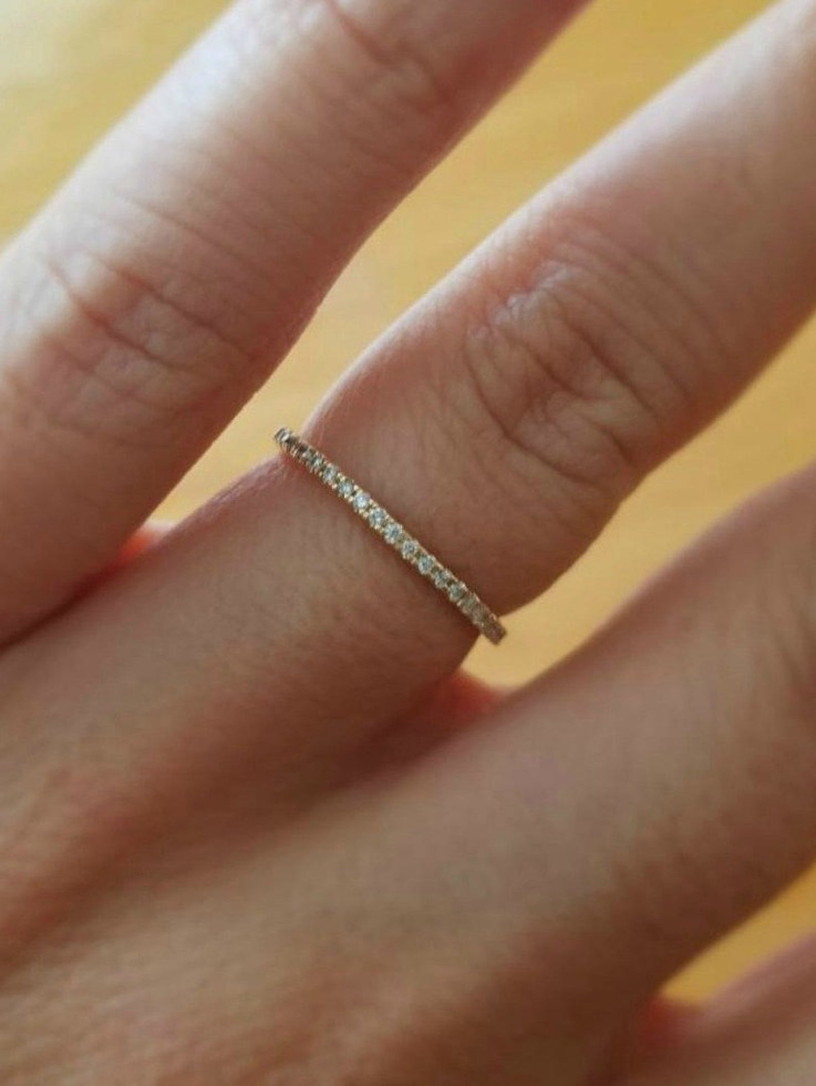 14K gold half eternity diamond wedding ring on hand, featuring a thin band with micro pave diamonds for elegance.