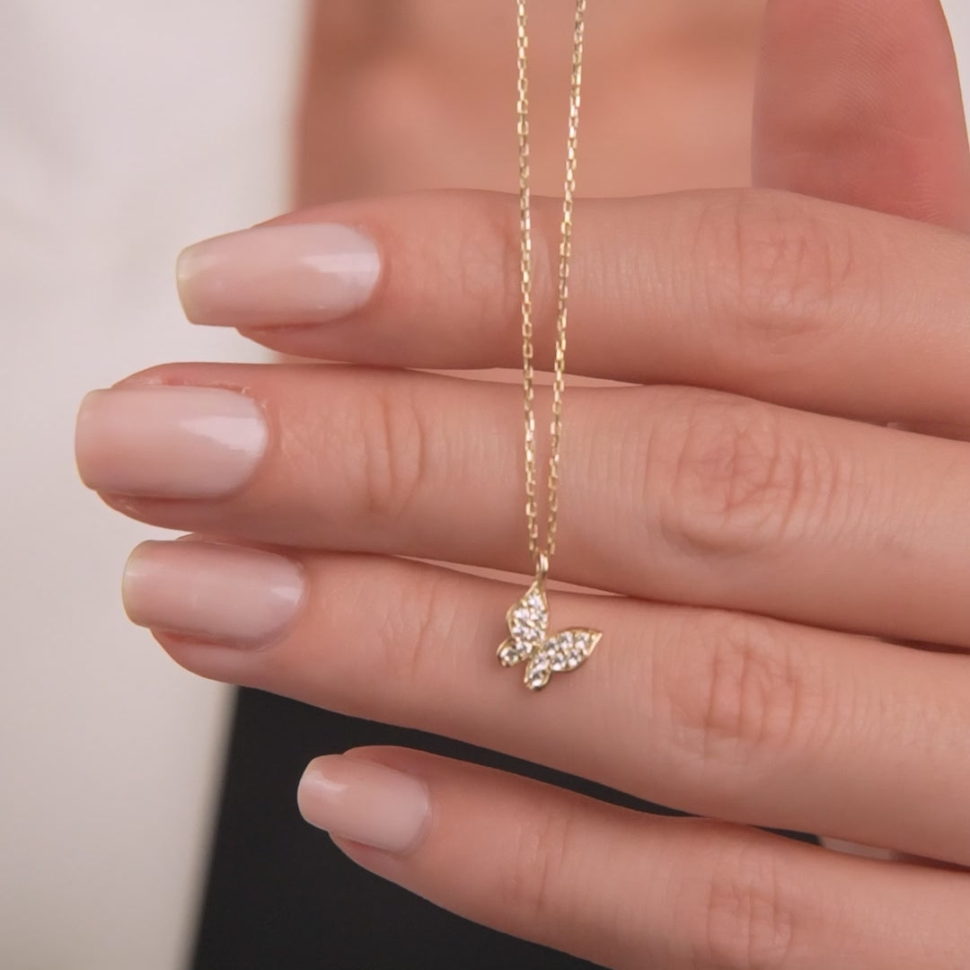 14K solid white gold minimalist butterfly necklace worn on a hand, showcasing its delicate design and CZ details.