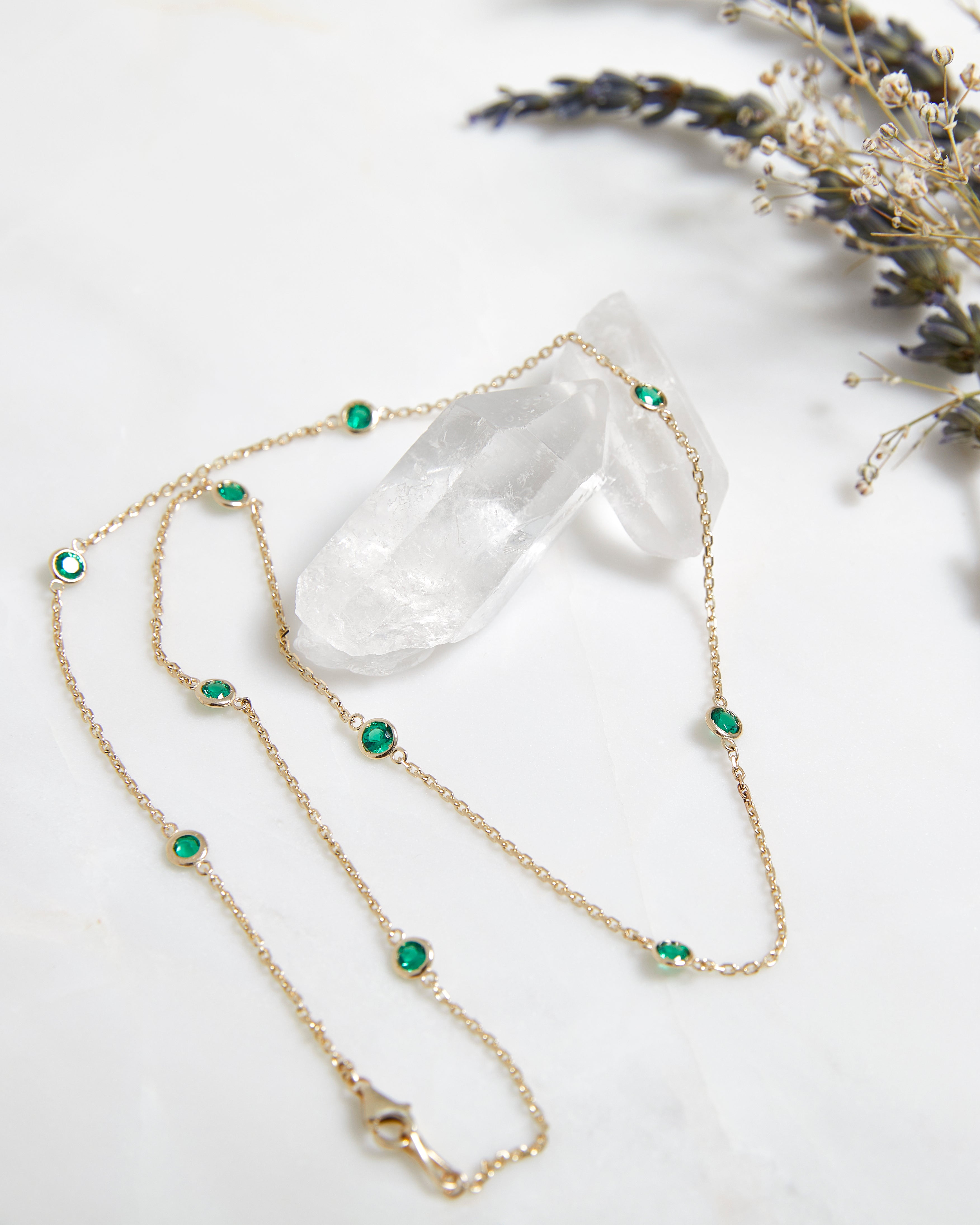 14K gold emerald station necklace featuring delicate bezel-set emeralds on an elegant chain.