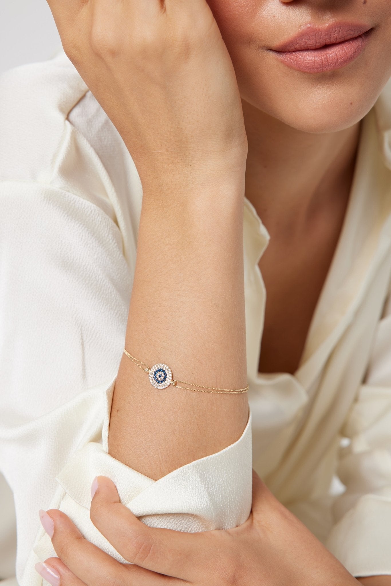 Model wearing a dainty 14K solid yellow gold evil eye bracelet with CZ accents, showcasing its minimalist design.