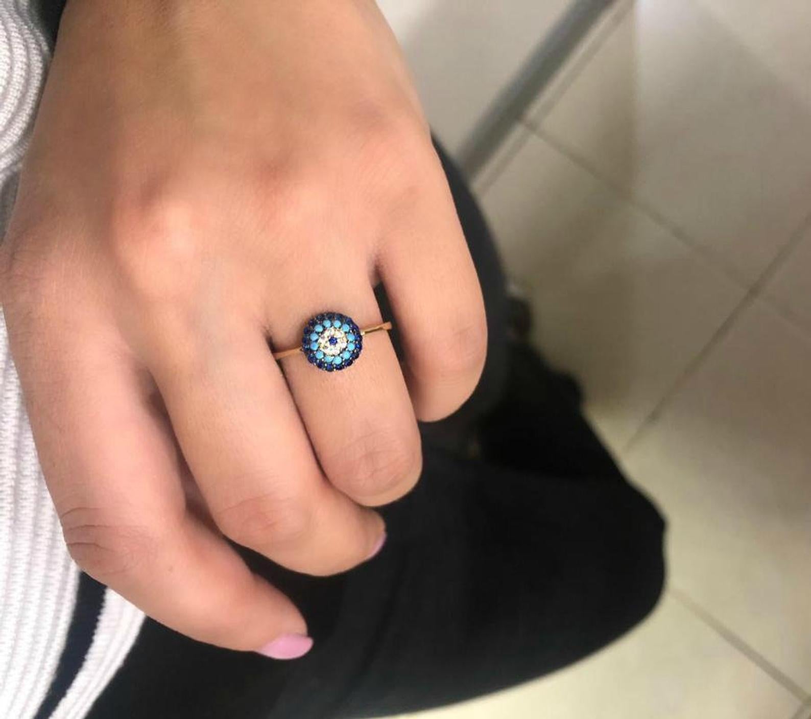 14K solid yellow gold turquoise evil eye ring worn on a finger, featuring a round blue and turquoise design.