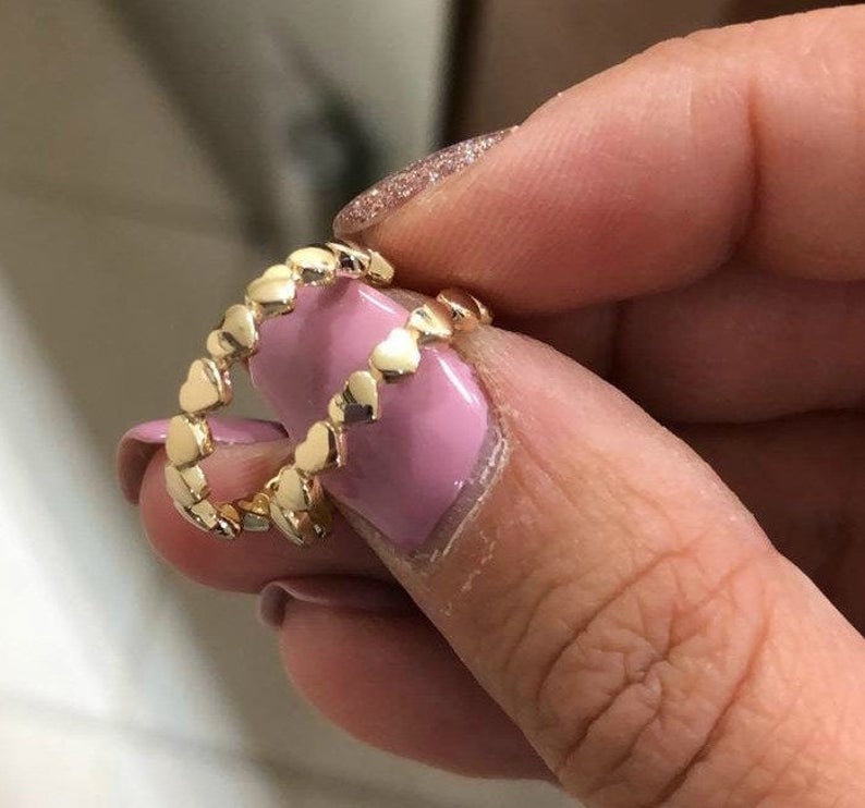 Elegant 14K solid yellow gold minimalist heart ring held between fingers with a pink manicure.