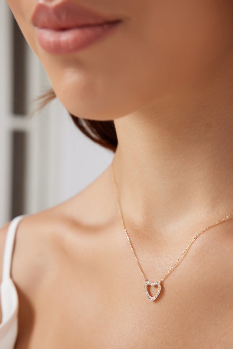 Close-up of a woman wearing a 14K solid yellow gold diamond heart necklace, showcasing its elegance and sparkle.