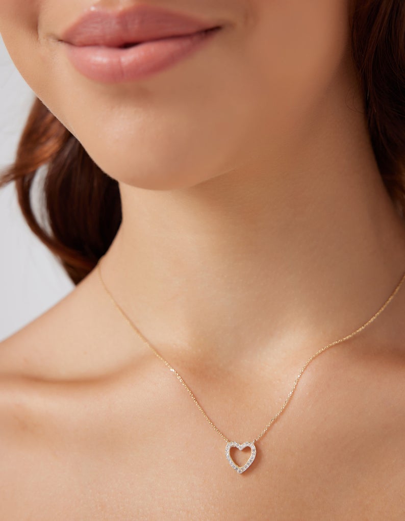Model wearing a 14K solid yellow gold dainty heart necklace with diamonds, featuring delicate design and sparkle.